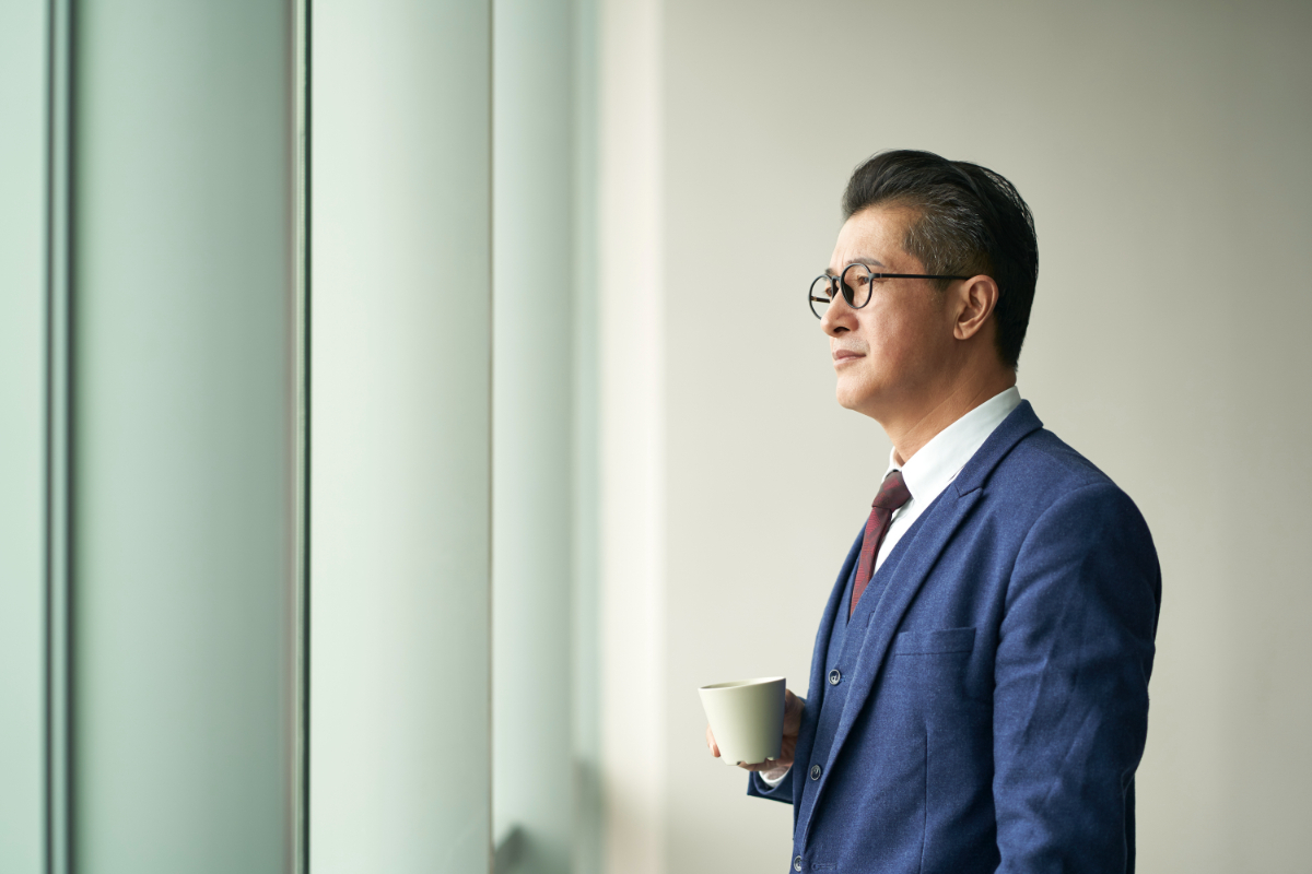 portrait of a asian business leader senior manager standing by window thinking