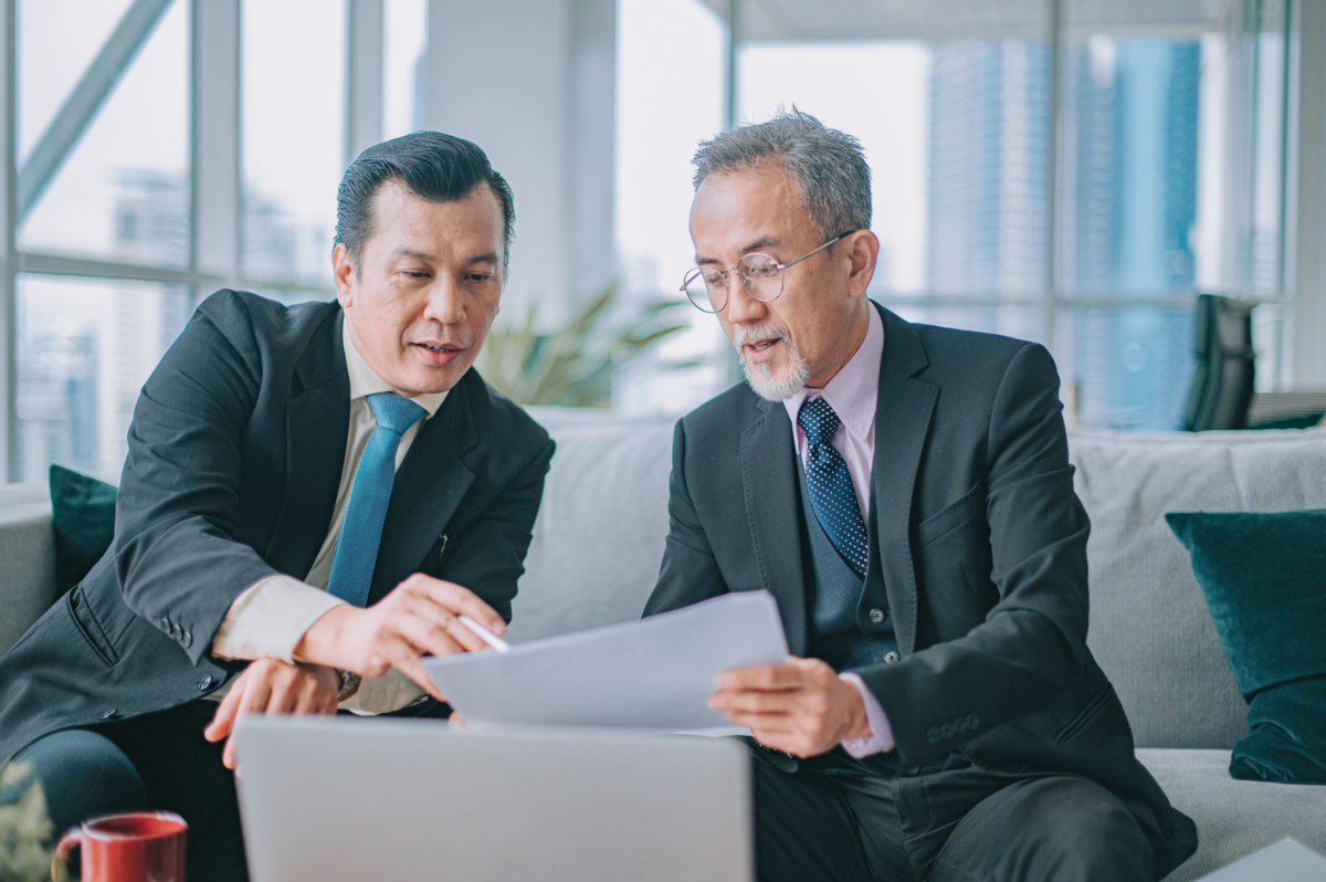 2 Asian mature businessmen discussion performance review business plan in office