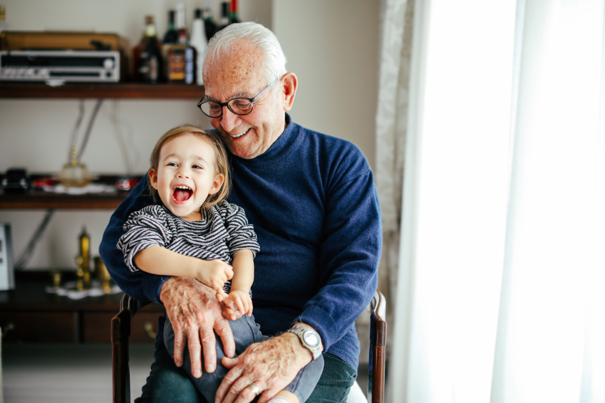 Happy family portrait of grandad sitting hugging grandchild